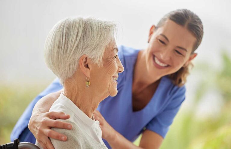 Older adult choosing clothing while a caregiver offers respectful assistance in a bright apartment.