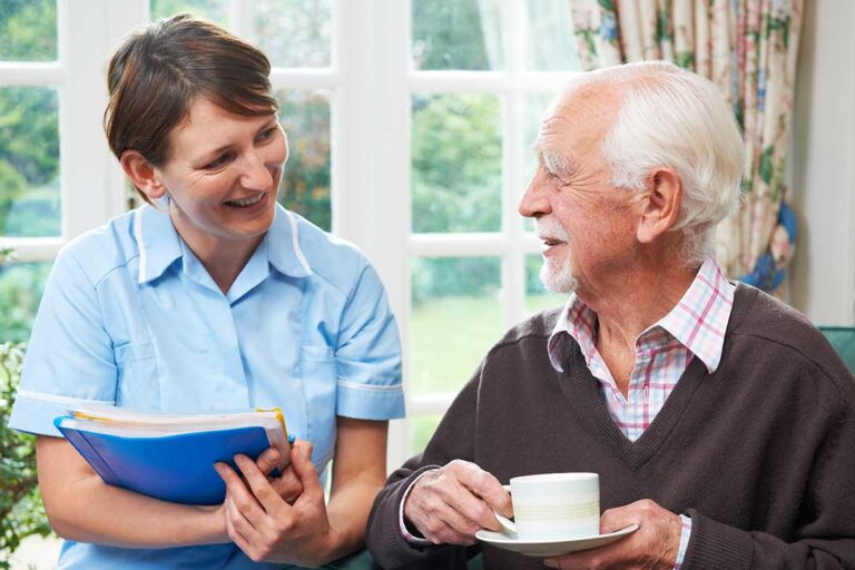 Older adult and family member reviewing health care documents together at a kitchen table.